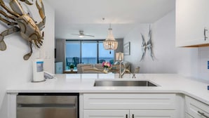 A modern kitchen with a large island, stainless steel appliances, and a view to the outside.