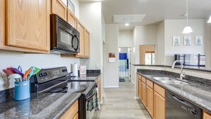 Eine moderne Küche mit Holzschränken, einem eingebauten Backofen und einer Arbeitsplatte aus Granit.