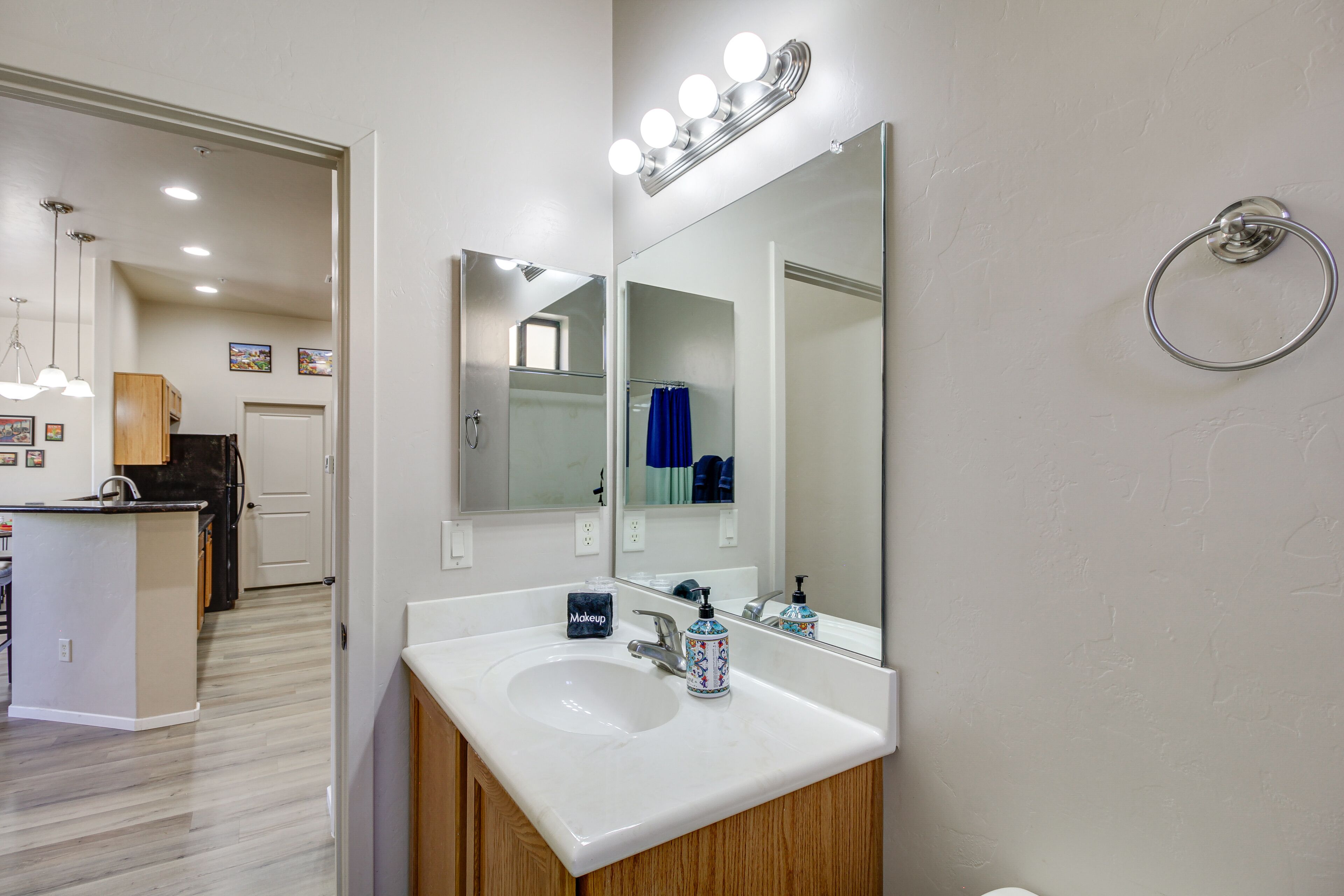 A modern bathroom with a large mirror, vanity, and a ring light.