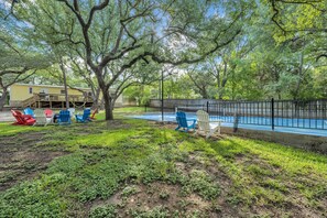 Un jardin avec une piscine, une terrasse couverte et un espace salon extérieur.