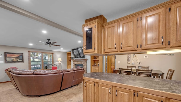 A spacious kitchen with wooden cabinets, a marble countertop, and a dining area with a table and chairs. - The Bird Nest- Bunkhouse, Sports Court, & Kayaks (Kingsland)