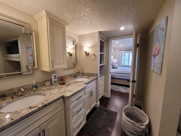 A bathroom with two sinks, a large mirror, and a walk-in closet.