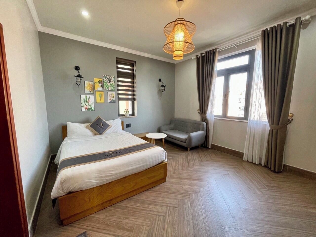 A bedroom with a bed, a small round table, a sofa, and a window with curtains.
