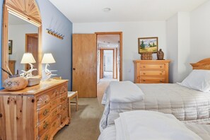 Ein Schlafzimmer mit einem Bett, einem Schminktisch, einem Spiegel und einer Tür zu einem weiteren Raum.