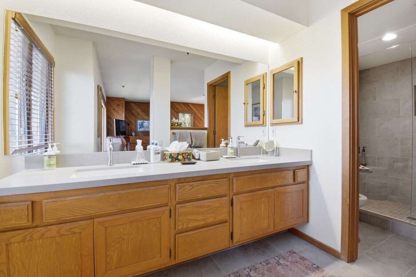 A modern bathroom with a large vanity, a shower area, and a large mirror.
