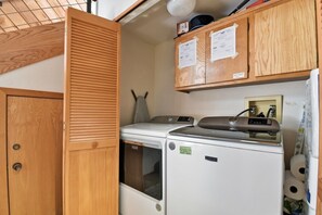 A compact laundry room with a washing machine, dryer, and wooden cabinets above.