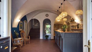 Una cocina amplia con una isla central, un comedor con sillas de mimbre y una escalera que conduce a un nivel superior.