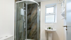 A bathroom with a glass-enclosed shower, a white sink, a window, and a toilet. - Harcourt 1D: 2BR Flat with Parking in Newark (Newark-on-Trent)