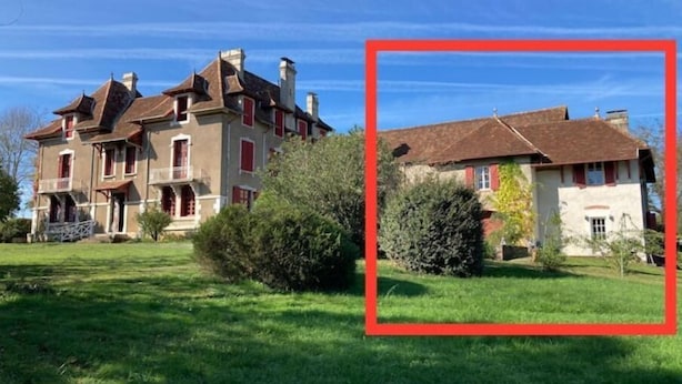 Ein großes, zweistöckiges Haus mit einem markanten Balkon im ersten Stock, umgeben von einem gepflegten Rasen.