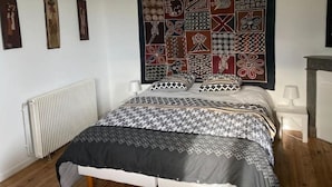 Ein Schlafzimmer mit einem gemusterten Bettbezug, einem Kopfteil mit geometrischem Design und einem Heizkörper an der Wand.