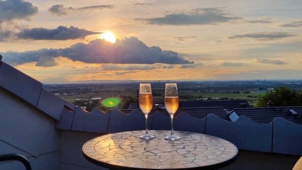 Two glasses of champagne on a tiled table with a scenic view of the sunset and landscape. - Moderne Ferienwohnung mit Atemberaubender Aussicht bei Heidelberg (Dossenheim)