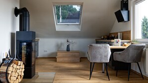 A modern kitchen with a skylight, a wood-burning stove, and two grey chairs. - Moderne Ferienwohnung mit Atemberaubender Aussicht bei Heidelberg (Dossenheim)