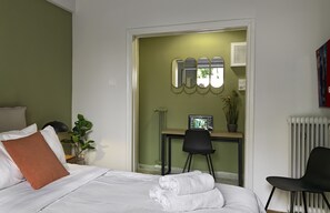 A hotel room with a bed, a desk, a chair, a radiator, and a wall-mounted mirror. - A Studio at a Super Prime Location (Athens)
