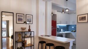 A modern kitchen with white cabinets, a red refrigerator, and a bar area with stools. - Modern 1BR Apt, Next to Goulandris (Athens)
