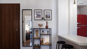 A modern kitchen with a white countertop, a red refrigerator, and a black metal shelf unit with decorative items. - Modern 1BR Apt, Next to Goulandris (Athens)