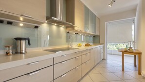 Een moderne keuken met een groot eiland, roestvrijstalen apparatuur en uitzicht naar buiten.