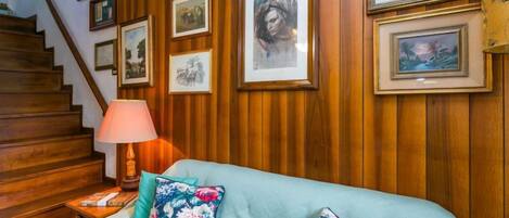 Ein Zimmer mit einer Holzwand, einer Treppe und einem Bett mit Blumenkissen.