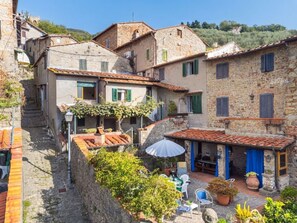 A narrow street with stone buildings, outdoor seating, and greenery. - La casa del Fale di Collodi by Interhome (Pescia)