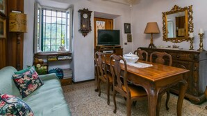 Una sala de estar acogedora con una mesa de comedor de madera, sillas, un sofá, un televisor y un ventilador de techo.