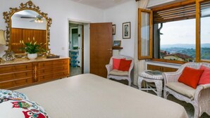 Un dormitorio con cama, cómoda, espejo y sillas de mimbre.