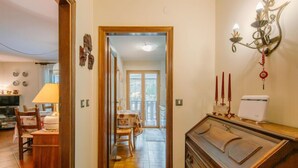 Un couloir avec un meuble en bois, un coin repas avec une table et des chaises, et un luminaire fixé au mur.