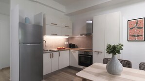 A modern kitchen with white cabinets, stainless steel appliances, and a dining area with a table and chairs. - A Luxurious 1BR Kolonaki Haven (Athens)