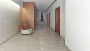 A hallway with a wooden panel, a potted plant, and a staircase leading to a door. - A Luxurious 1BR Kolonaki Haven (Athens)