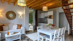 A cozy living room with a white sofa, a dining table with chairs, and a kitchen in the background. - Château De Kergonano, dans l'Orangerie by Interhome (Baden)