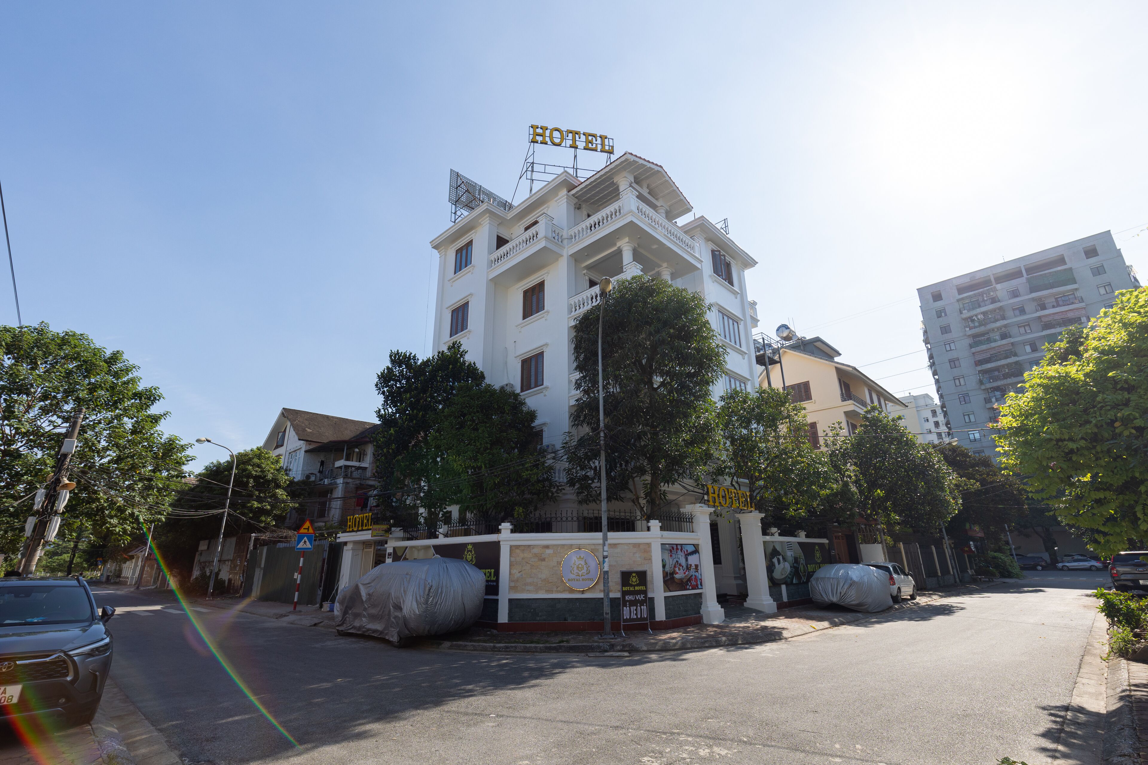 A hotel with a prominent 'HOTEL' sign on the roof, a gated entrance, and a covered parking area.