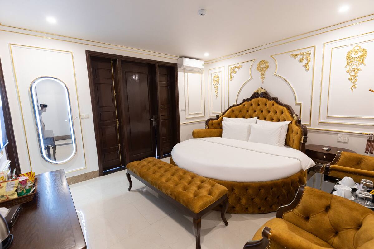A luxurious bedroom with a large bed, a bench, and two armchairs.