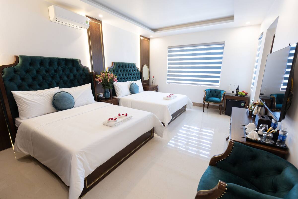 A hotel room with two beds, a sitting area, a TV, and a minibar.