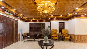 A lobby with a marble floor, a chandelier, a sofa, two armchairs, and a table with a vase. - Royal Hotel - Sai Dong - Long Biên (Hanoi)