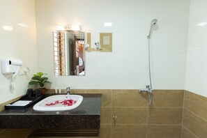 A bathroom with a sink, mirror, shower, and a potted plant. - Royal Hotel - Sai Dong - Long Biên (Hanoi)