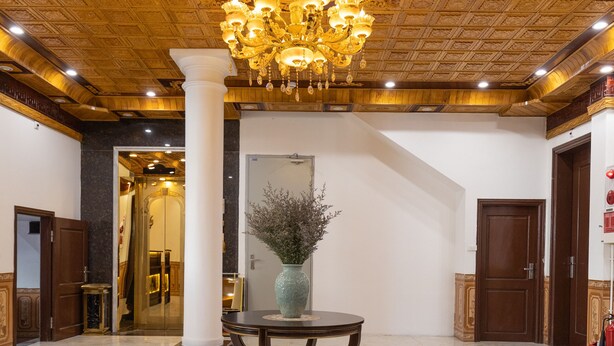 A lobby with a chandelier, a table with a vase, and a fruit bowl. - Royal Hotel - Sai Dong - Long Biên (Hanoi)
