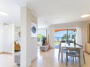 Ein modernes Wohnzimmer mit Essbereich, Fernseher und Meerblick.