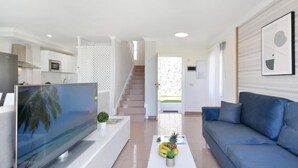 Una sala de estar moderna con un televisor de pantalla plana, un sofá azul y una mesa de centro con frutas.