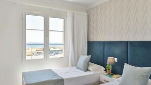 Habitación de hotel con dos camas, vista a la playa y pared con estampado.