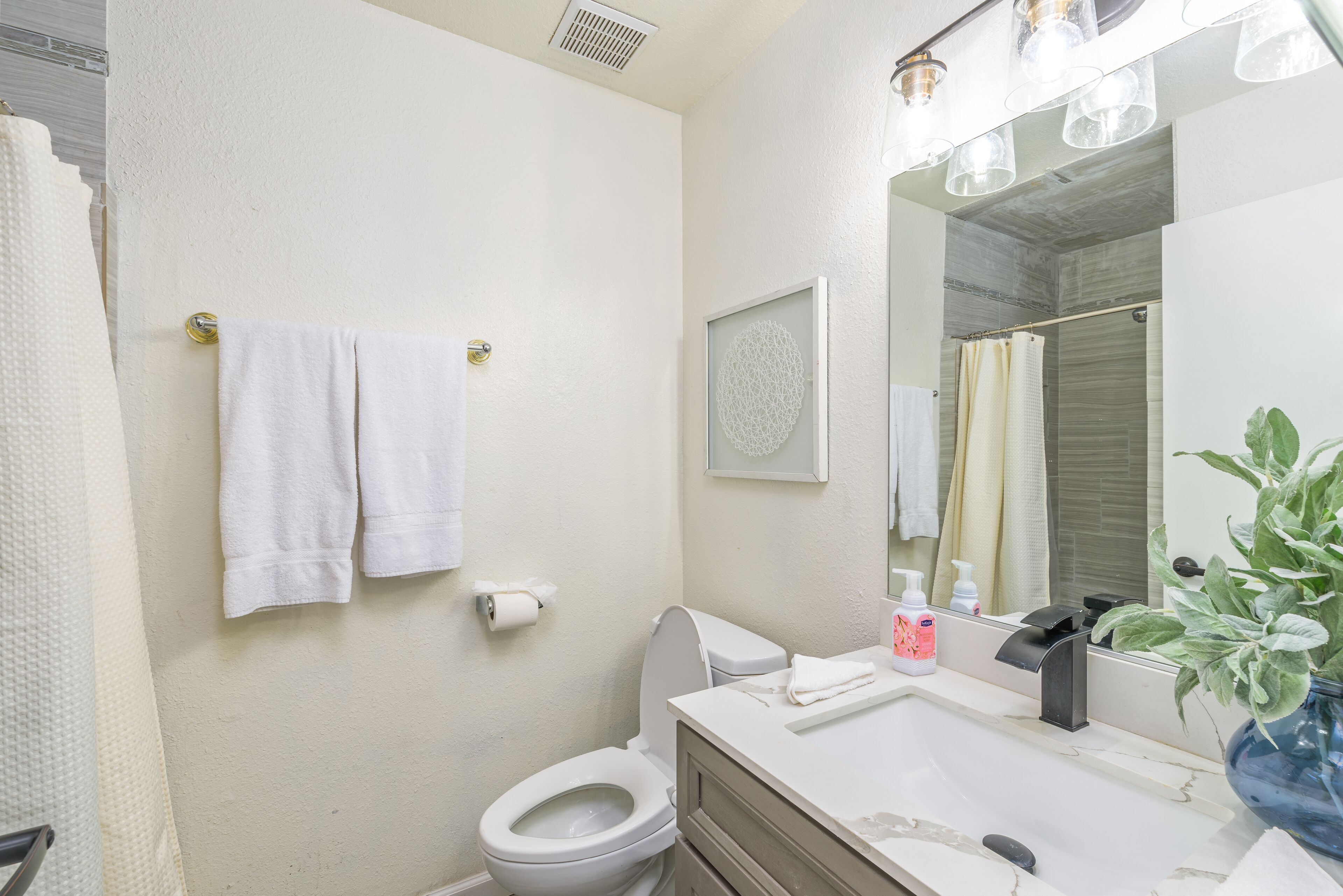 Un baño con inodoro, lavabo, espejo y toallero.