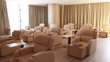Amplia habitación con varias zonas de estar, incluyendo sofás y sillones, distribuidos alrededor de mesas.