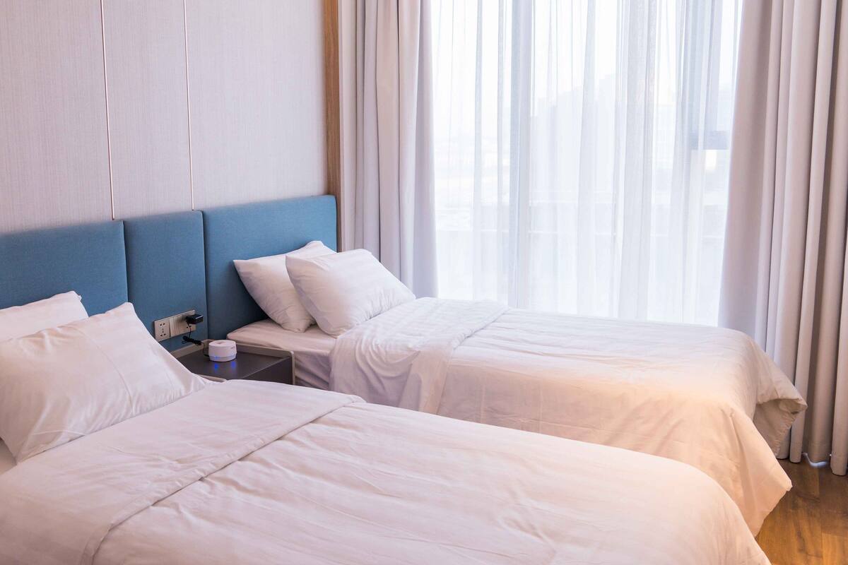 A hotel room with two beds, a nightstand, and a power outlet.