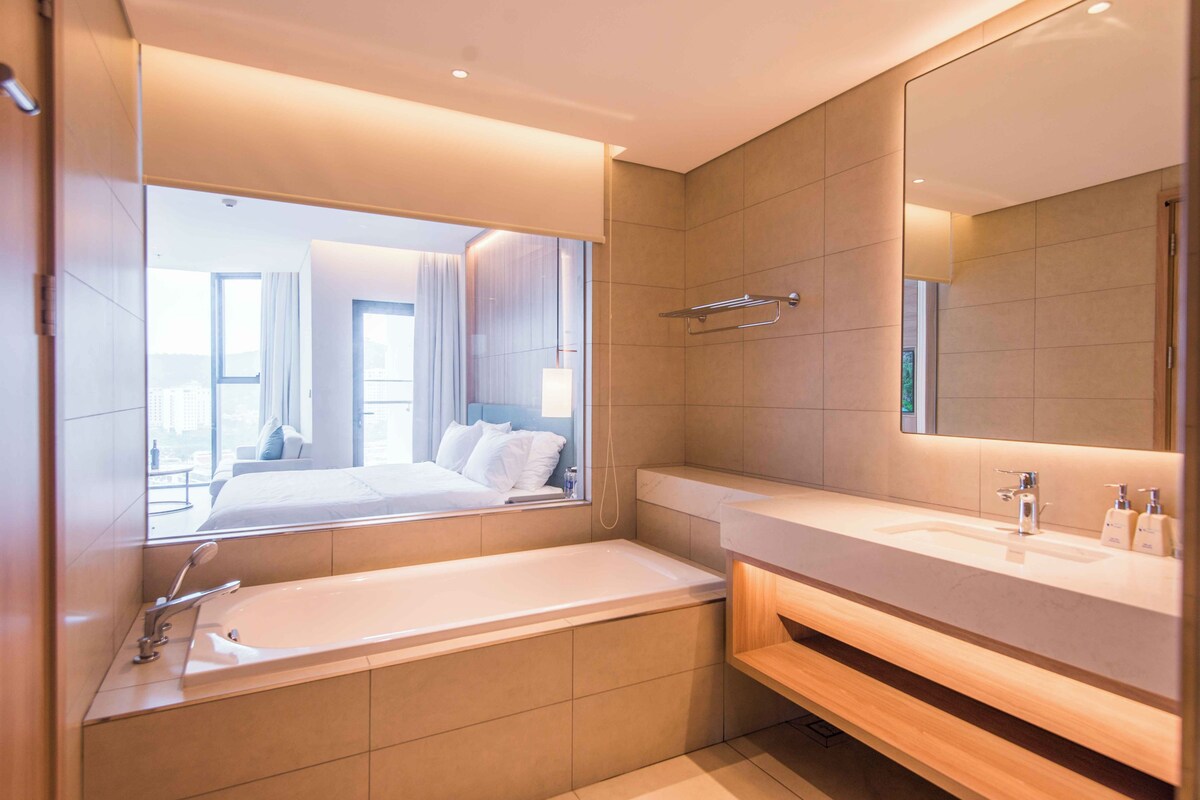 A modern bathroom with a large mirror, a bathtub, and a vanity with a sink.