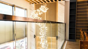A modern interior with a glass partition, wooden paneling, and a hanging floral decoration. - Anstay Residence by A La Carte Hạ Long (Bai Chay)