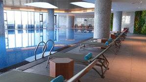 A modern indoor pool area with sunlit spaces, lounge chairs, and a view of the sky. - Anstay Residence by A La Carte Hạ Long (Bai Chay)