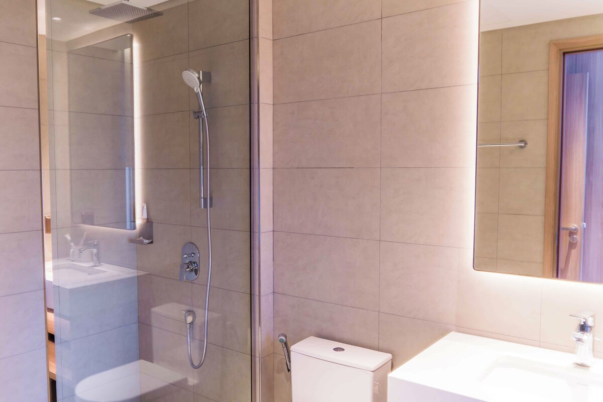 A modern bathroom with a glass-enclosed shower, a toilet, and a sink.