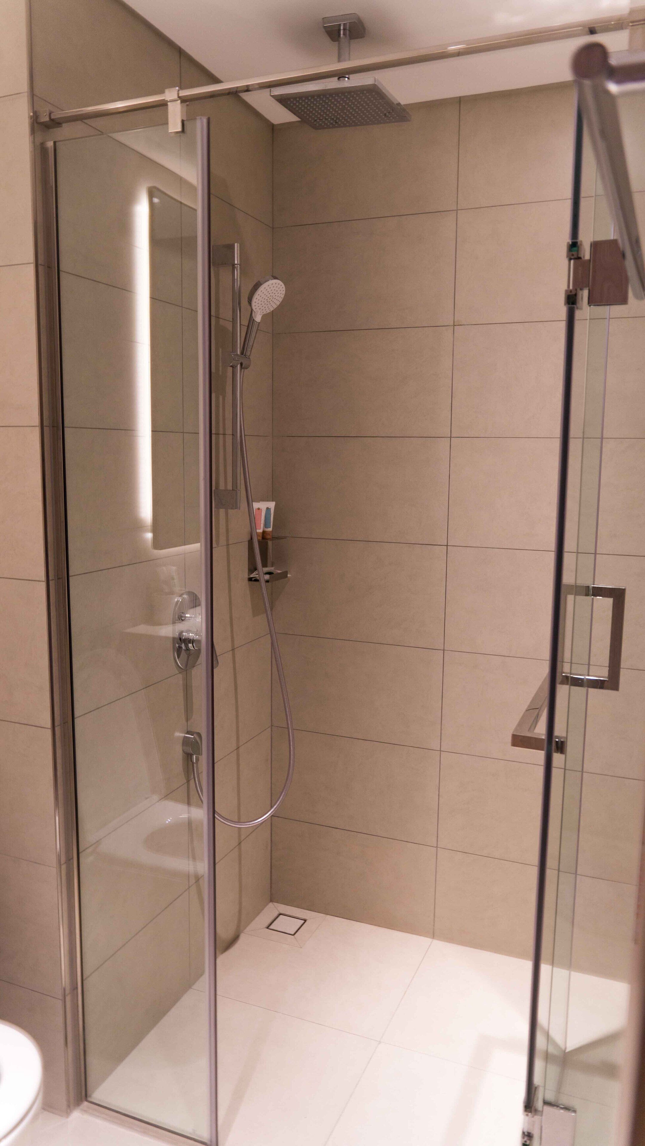 Een douche met glazen wanden, een handdouche en een douchekoof.