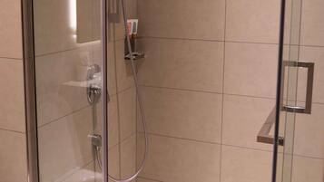 Een douche met glazen wanden, een handdouche en een douchekoof.
