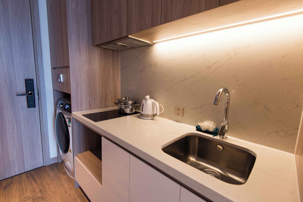 A modern kitchen with a built-in washing machine, a coffee maker, and a stainless steel sink.