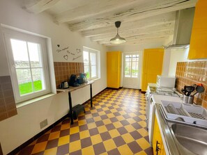 Une cuisine avec des meubles de couleur jaune, un carrelage à motifs et une fenêtre donnant sur un jardin verdoyant.