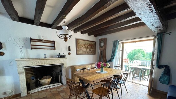 A dining area with a wooden table and chairs, a fireplace, and a view of the outdoors.