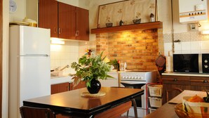 A kitchen with wooden cabinets, a brick wall, a white refrigerator, a stove, and a dining table with chairs.